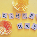 Scrabble letters spelling Mother's Day on yellow background
